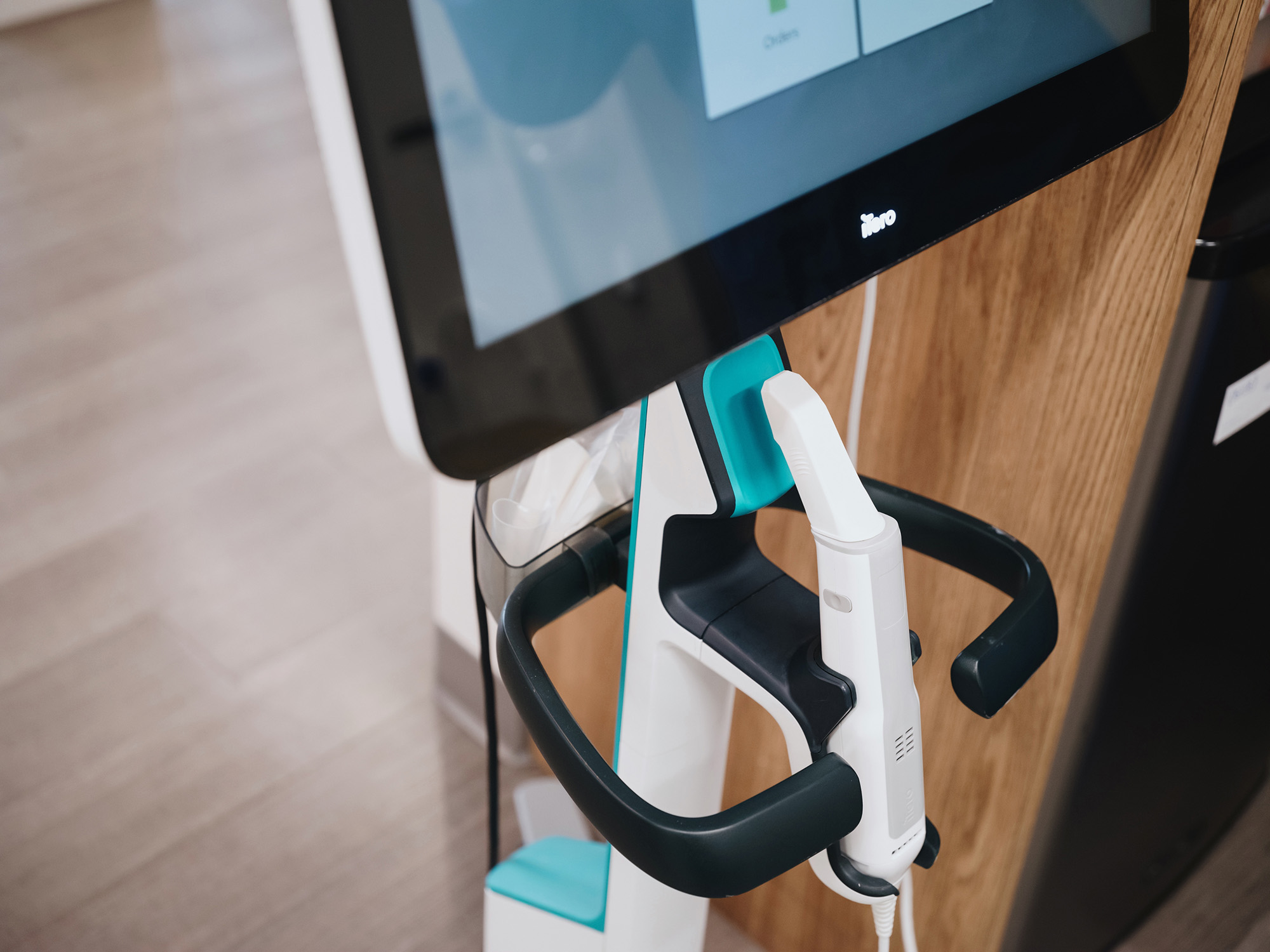Close-up of a medical or dental device with a white handheld scanner attached to a monitor on a stand.