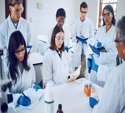 Group of medical students wearing lab coats, gloves, and safety goggles participating in a laboratory session.