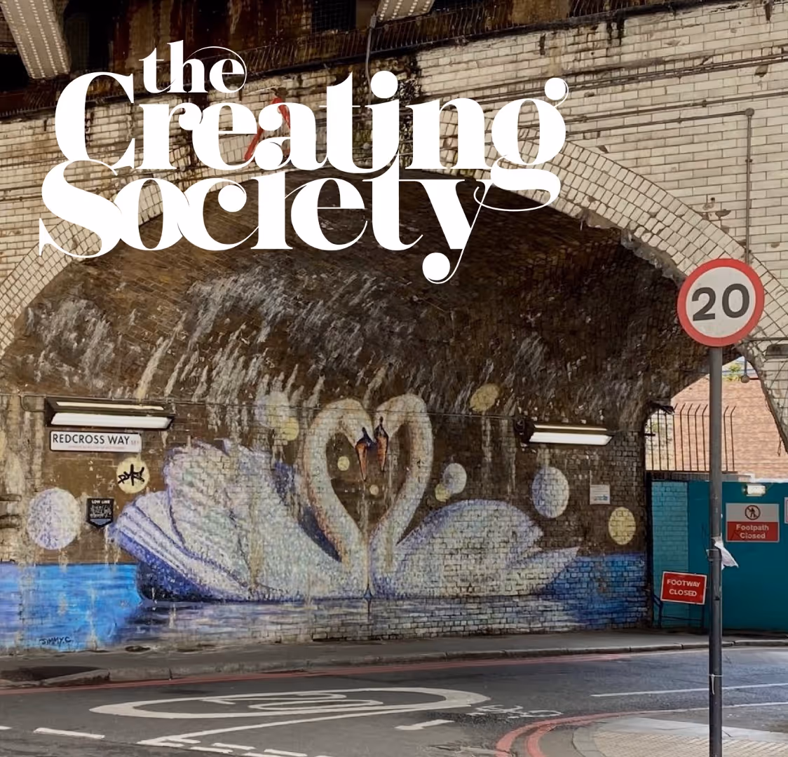 Muurschildering van twee zwanen die samen een hart vormen onder een stenen boog aan Redcross Way, met verkeersbord van 20 km/u en voetpad gesloten bord.