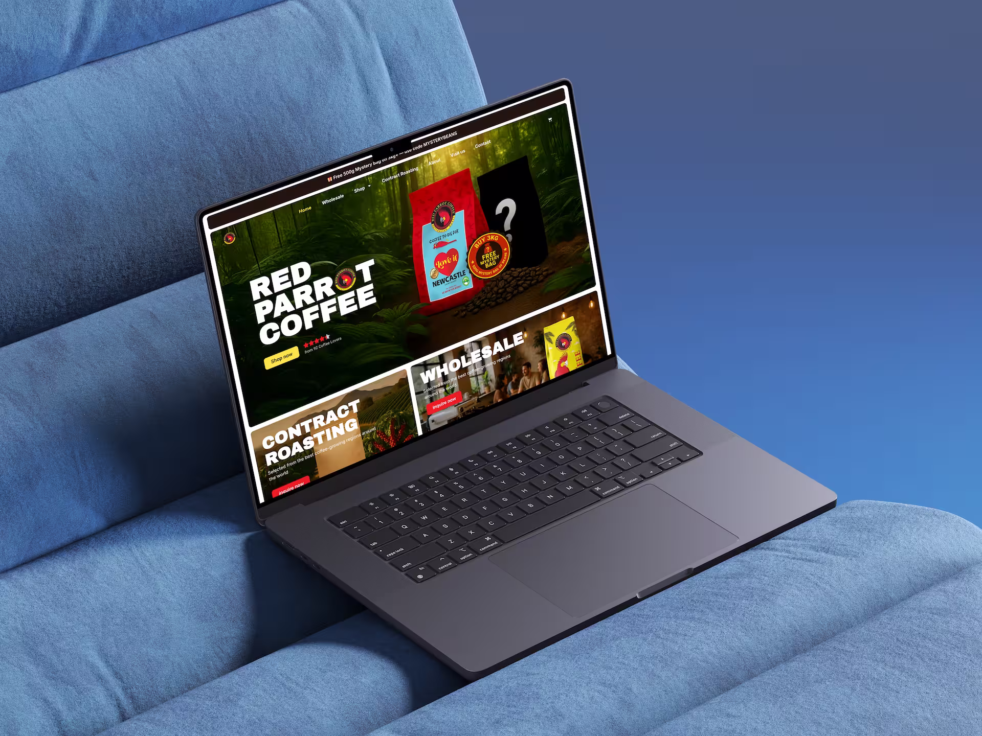 Open laptop showing Red Parrot Coffee website with product images and menu on a blue couch.