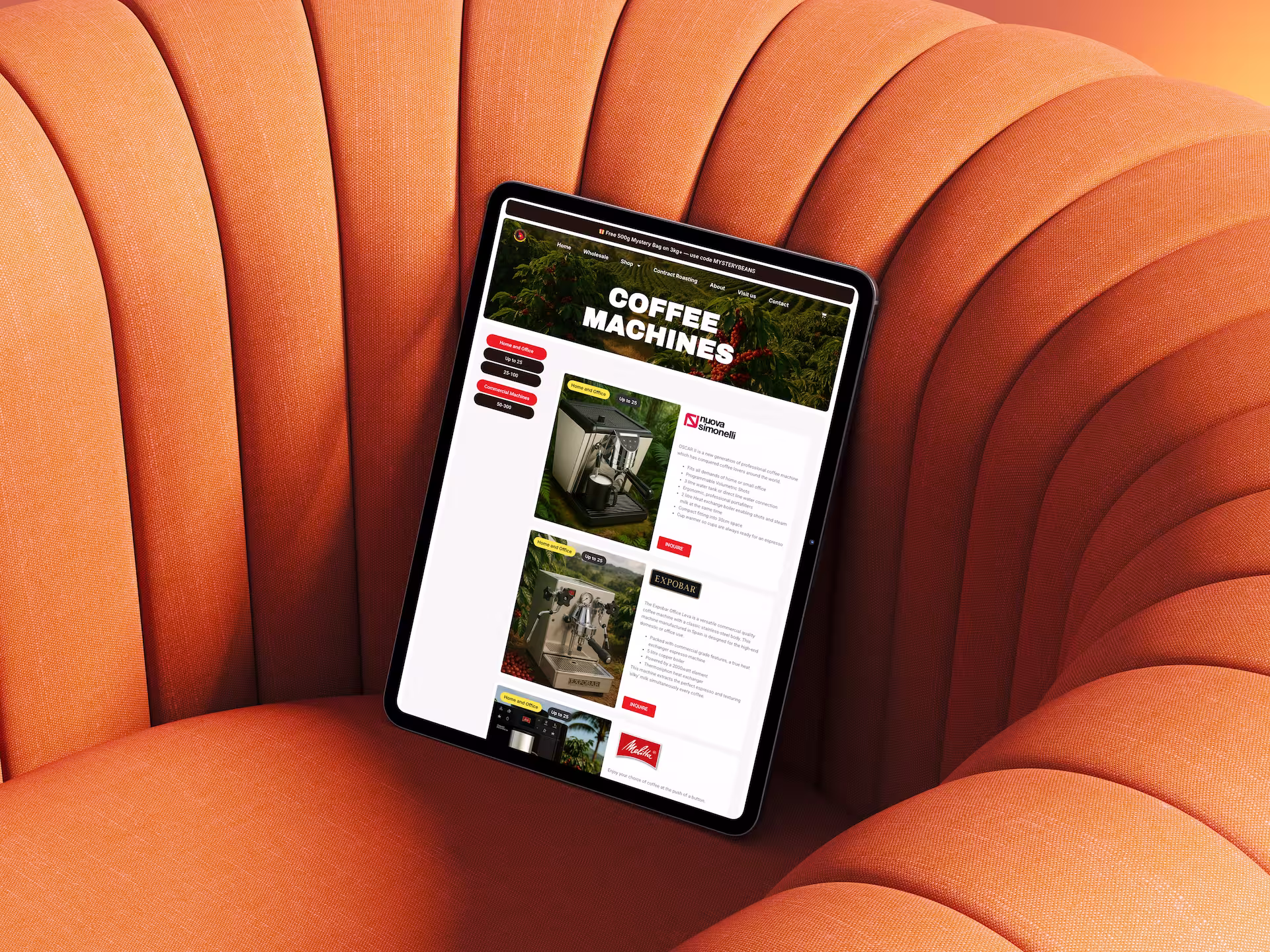 Tablet displaying a website page titled 'Coffee Machines' with images and details of different espresso machines, resting on an orange upholstered chair.