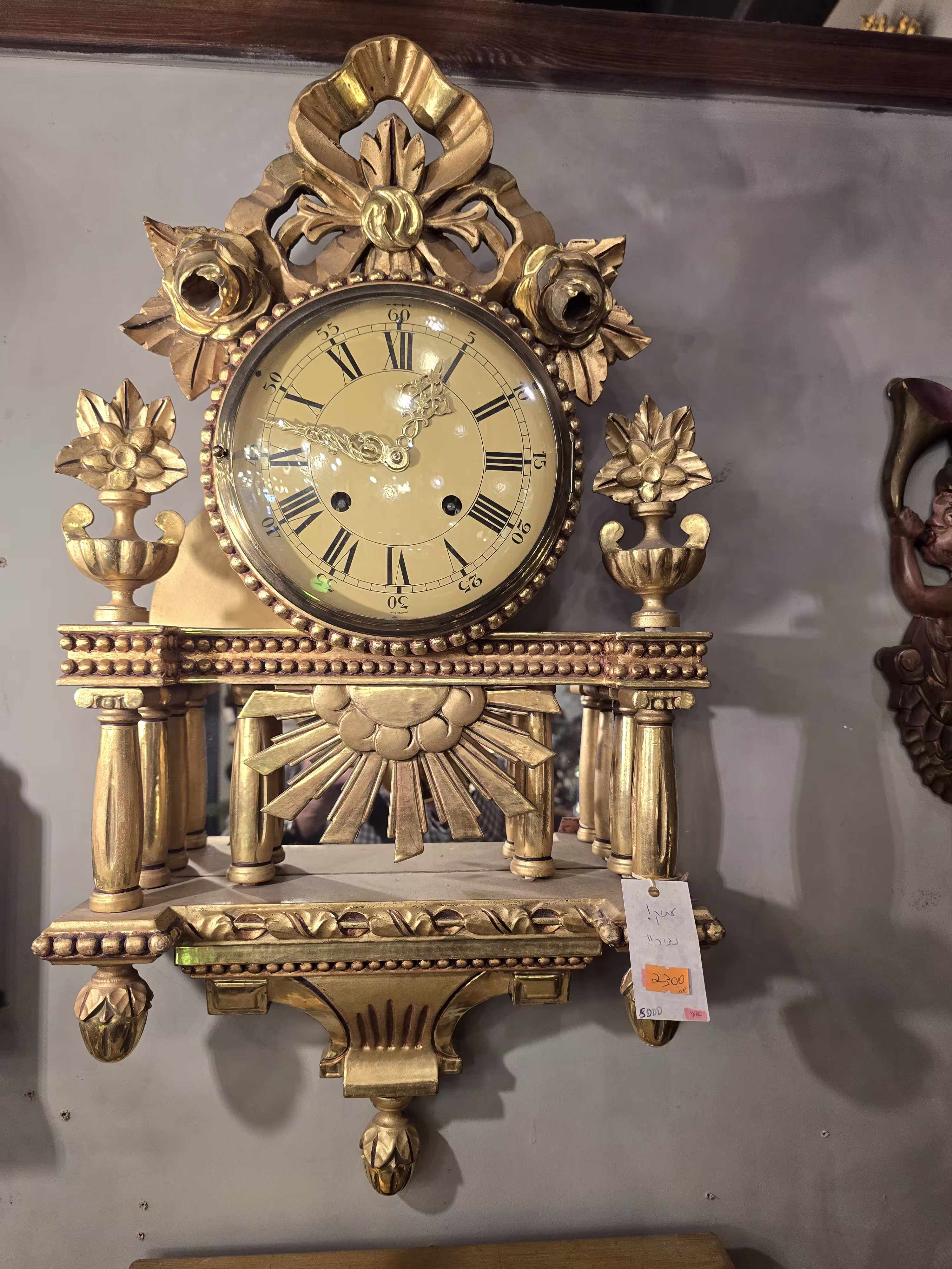 שעון קיר עתיק זהב עם קישוטי פרחים ואלמנטים קלאסיים.