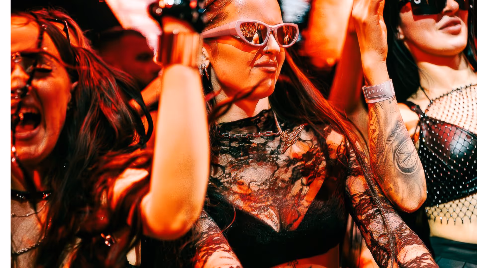 Group of young women dancing and enjoying themselves at a party with vibrant red lighting.