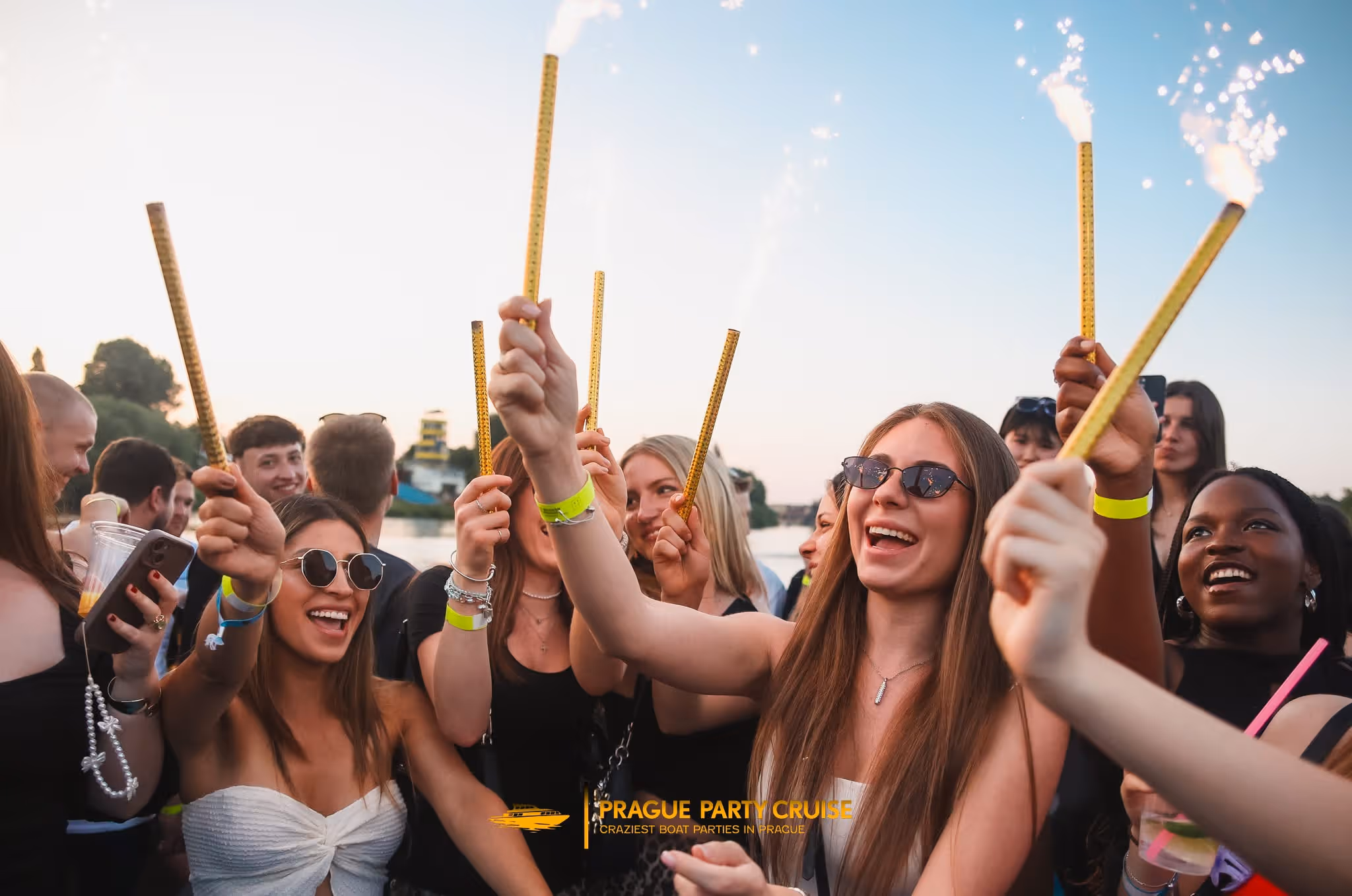 Crowded nightclub scene with a DJ performing and people dancing and taking photos under red lighting.