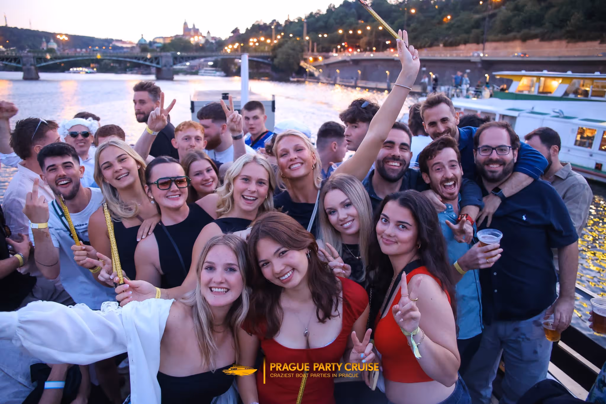 Group of young people raising cocktails and smiling in a dimly lit nightclub.