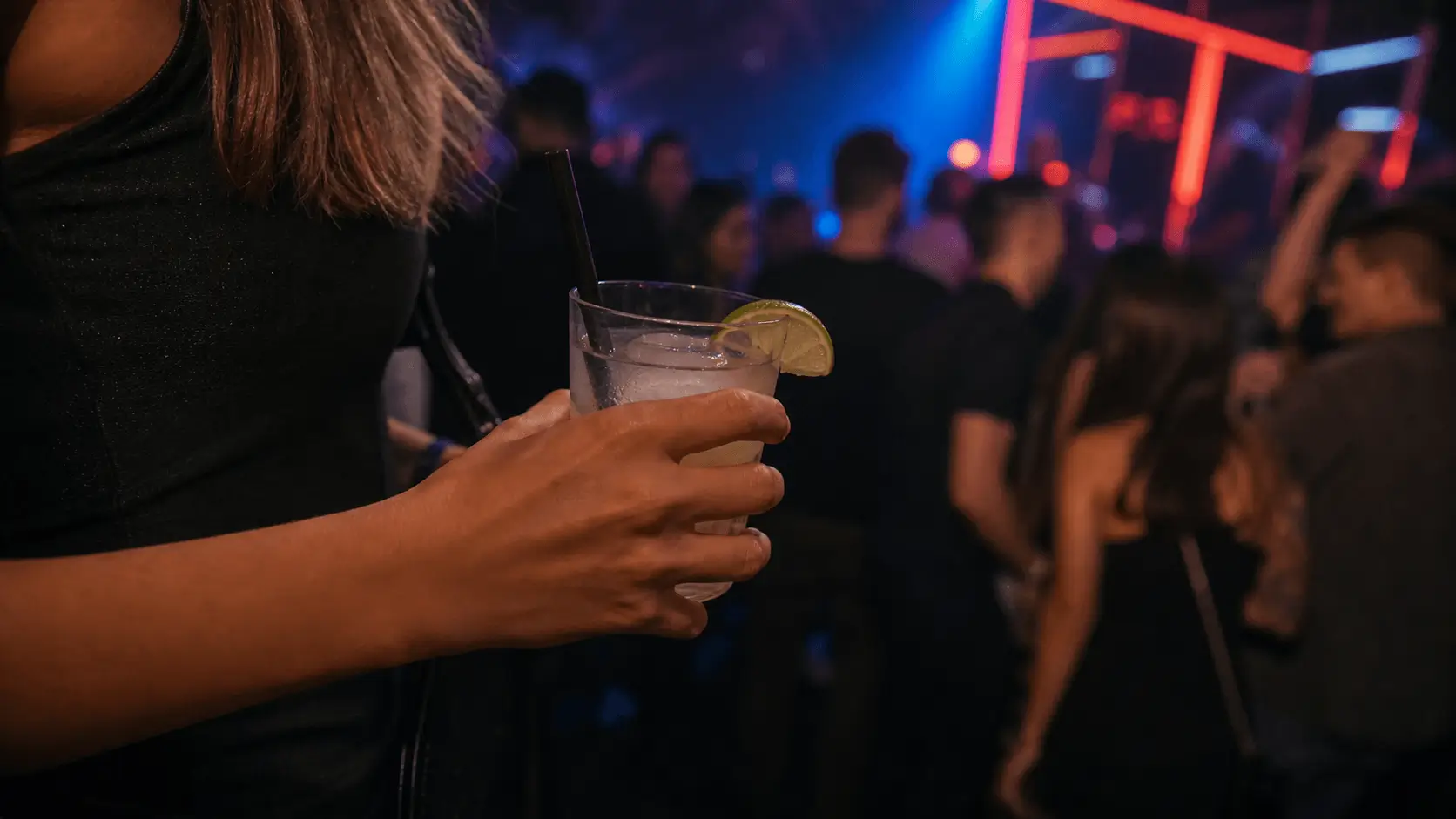 Hand holding a cocktail safely in a crowded nightclub