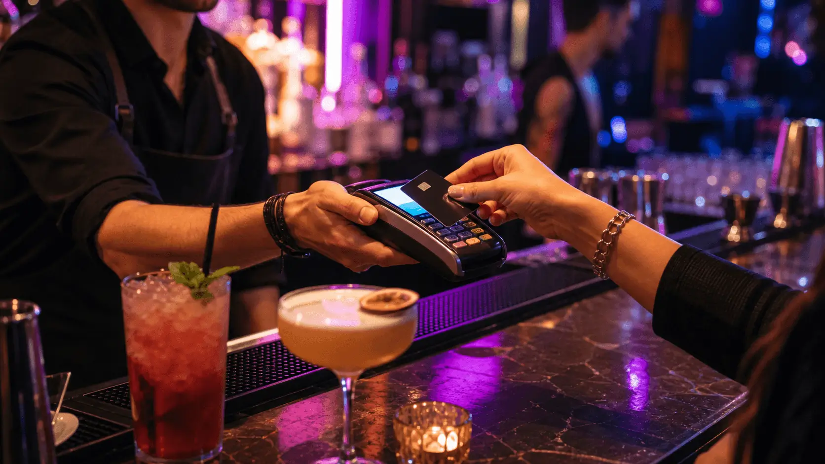 Contactless card payment at a neon-lit cocktail bar