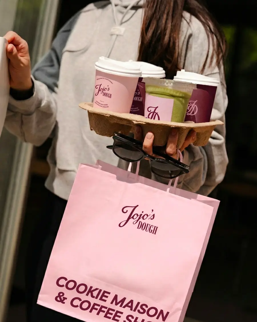 Client Jojo’s Dough emportant des boissons dans des gobelets logotypés avec un sac de la marque