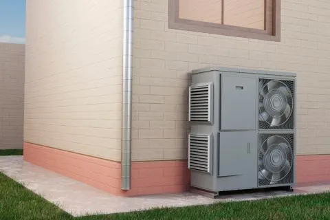 Outdoor air conditioning unit with two large fans installed against a beige brick house wall with pink lower trim.