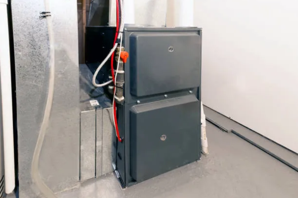 Modern gray HVAC furnace unit installed in a clean basement corner with connected ductwork and wiring.