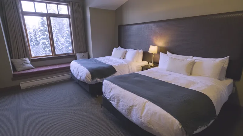 Two queen beds viewed from beside the guestroom window