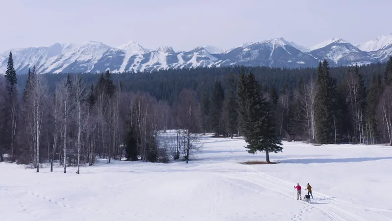 Two people on a snowy trail with distant mountain views