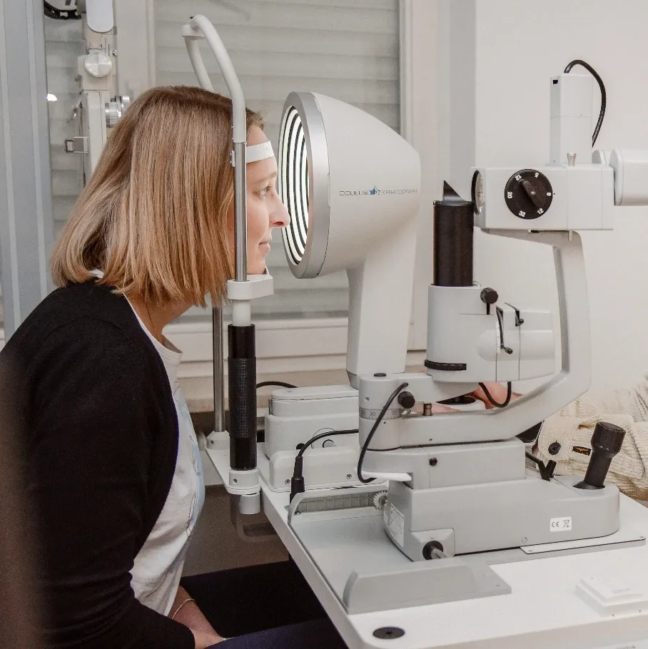 Frau bei einer Augenuntersuchung mit einem Keratograph-Gerät in einer Arztpraxis.