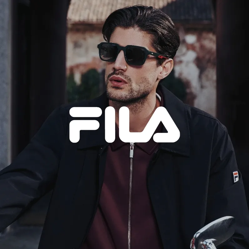 Markenbild Fila. Junger Mann mit dunkler Sonnenbrille und schwarzer Jacke mit FILA-Logo sitzt draußen.