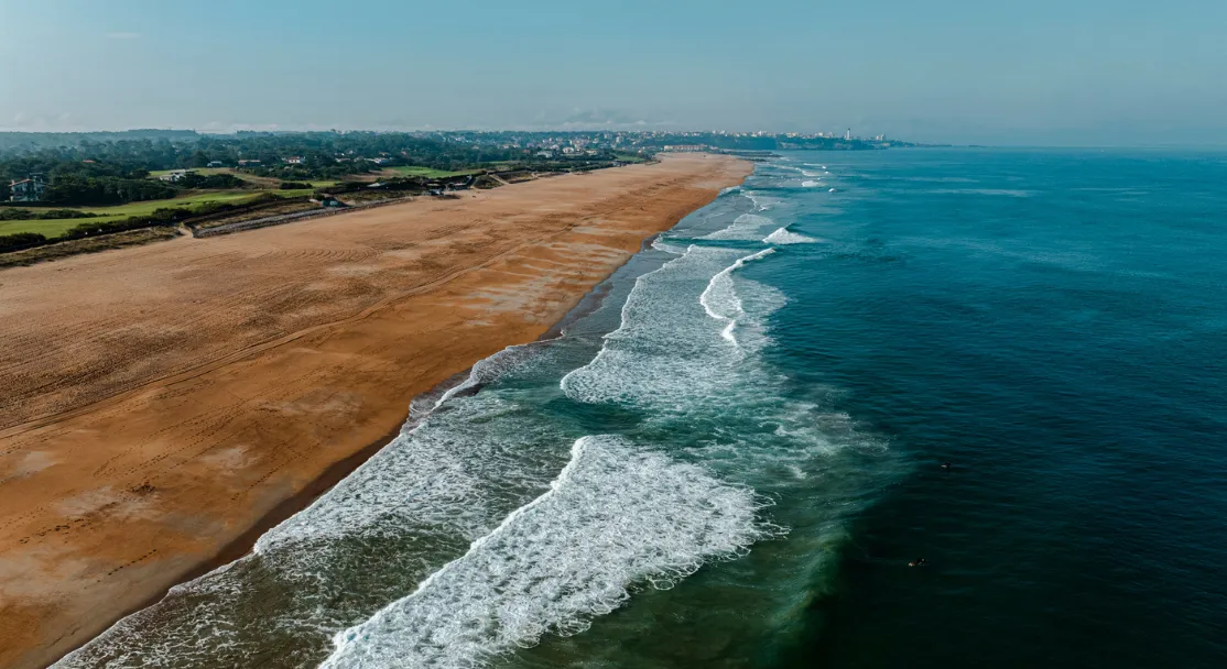 Vue aérienne du littoral d’Anglet avec plage de sable, vagues et végétation en arrière-plan