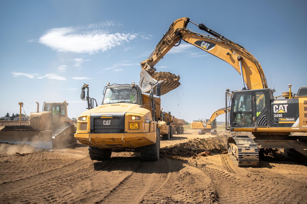 Kloubové dampry Cat 735 z flotily firmy DriveStone čekají v řadě, až je pásové rypadlo naplní odtěženým materiálem v oblasti mezi Újezdem nad Lesy a Koloději.