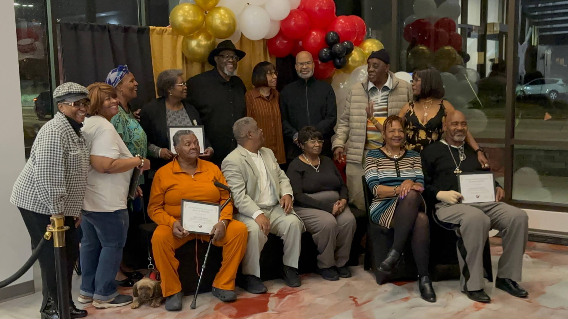 Group of elders posing together indoors at a Supporting Healthy Black Elders community celebration, some holding certificates