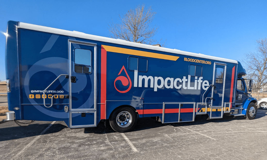 ImpactLife mobile blood donation bus parked outdoors at a community event location.