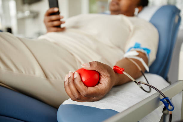 Person donating blood while resting in a medical chair, holding a stress ball