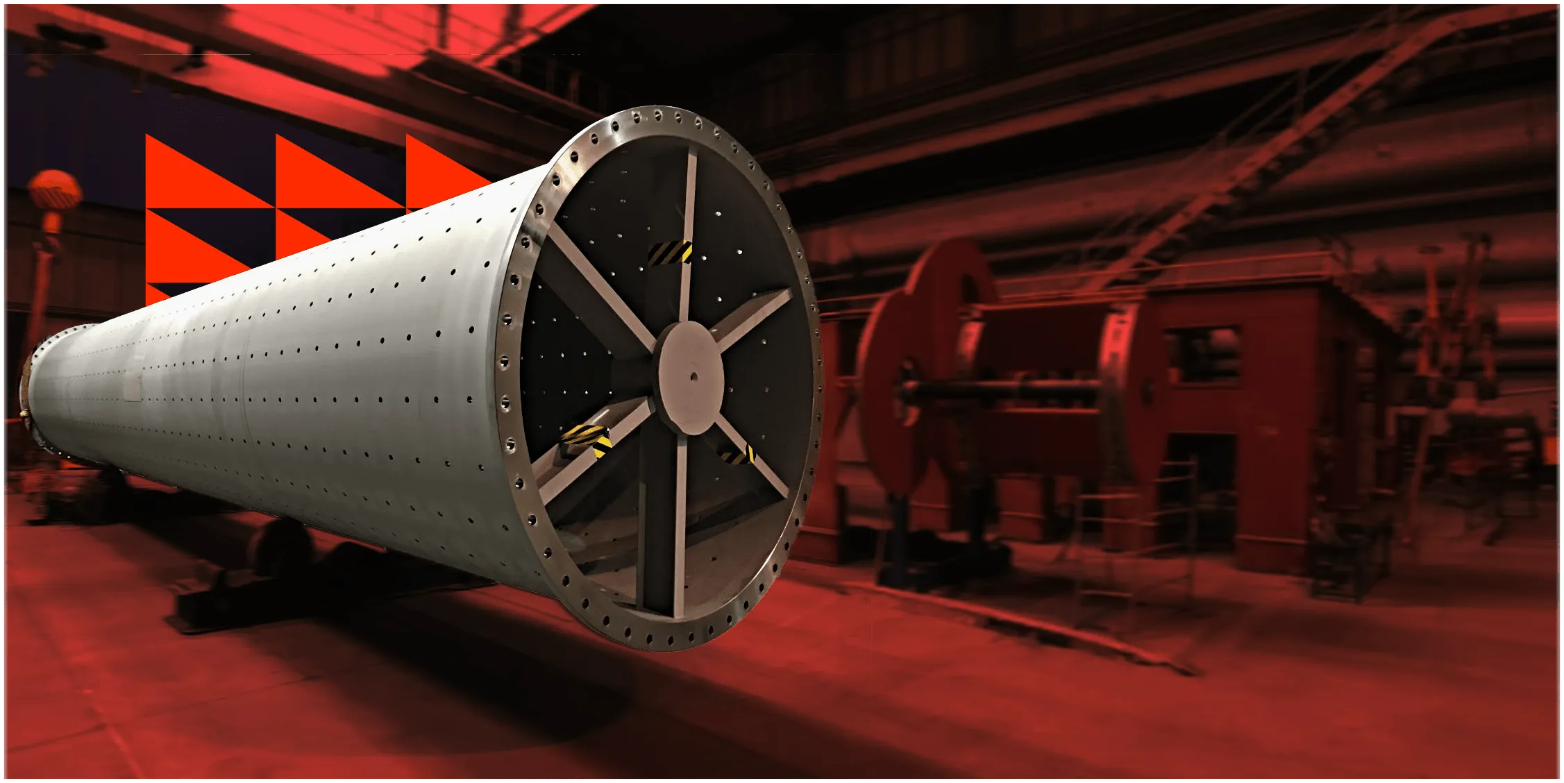 Velká kovová průmyslová trubka s výztužnými žebry v červeně osvětlené hale.