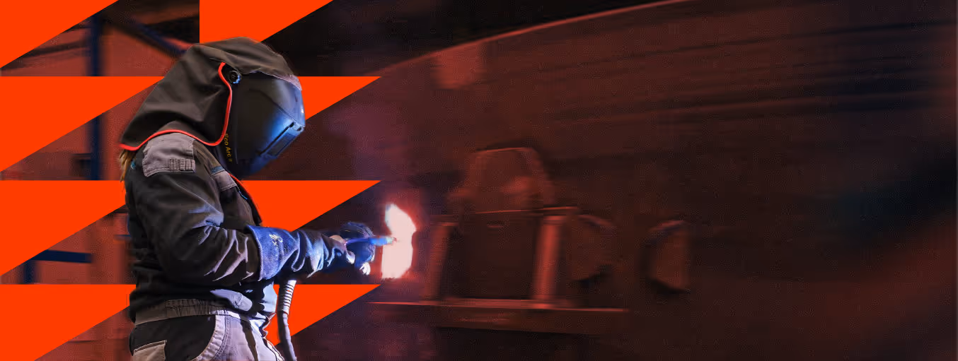 Osoba v ochranném oděvu a helmě provádí svařování s jasným plamenem v průmyslovém prostředí.