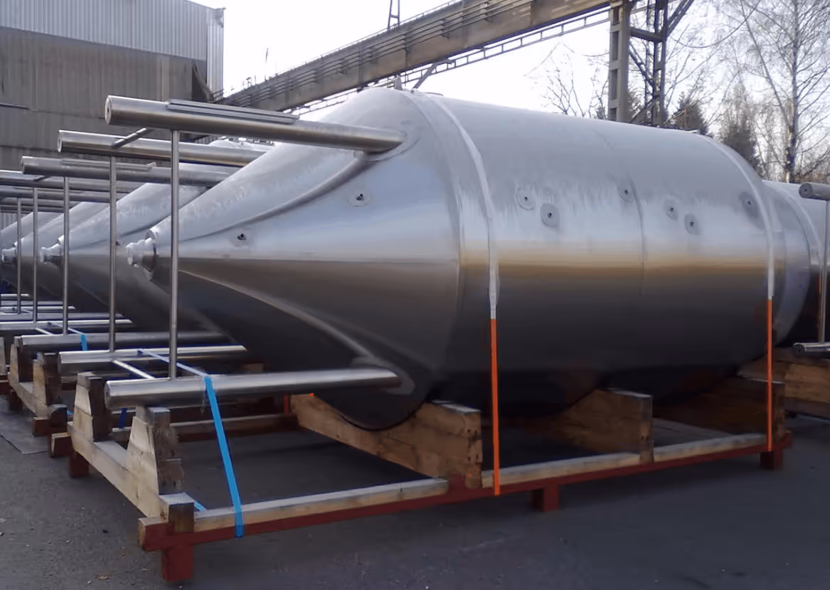 Two large metal industrial containers loaded on a flatbed semi-trailer in the open.