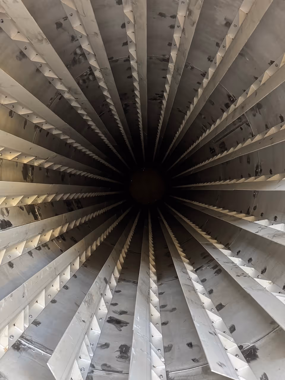 Large industrial cylindrical metal equipment with red-brown color inside the production hall.