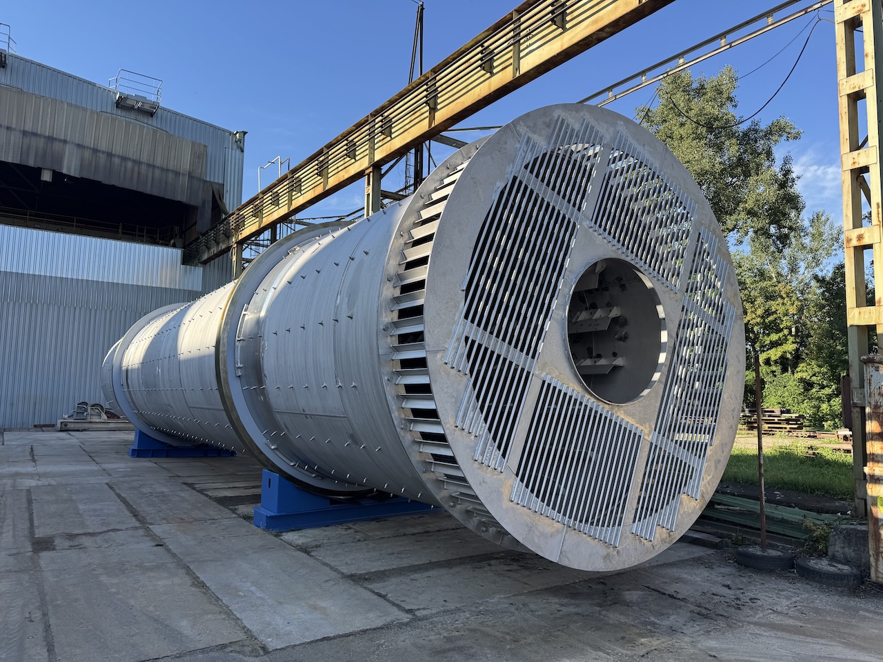 Dvě velké kovové průmyslové nádoby naložené na plošinovém návěsu na otevřeném prostranství.