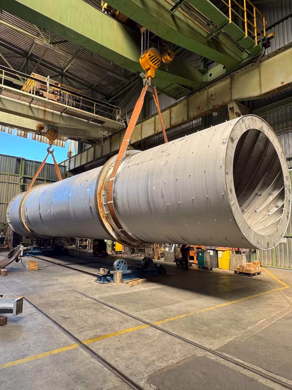 Large metal industrial equipment lying on concrete under a clear sky.