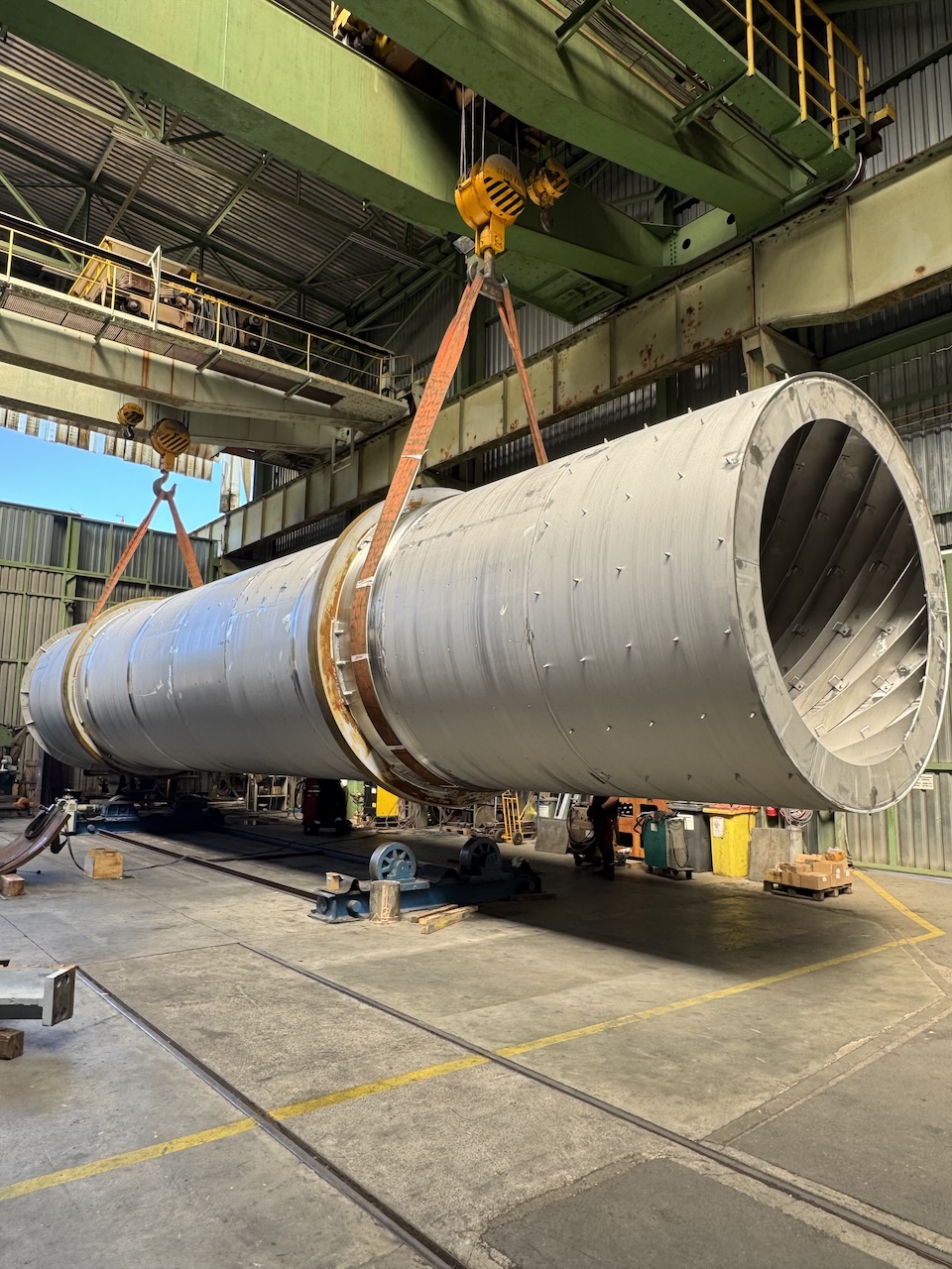 Velké kovové průmyslové zařízení ležící na betonu pod jasnou oblohou.