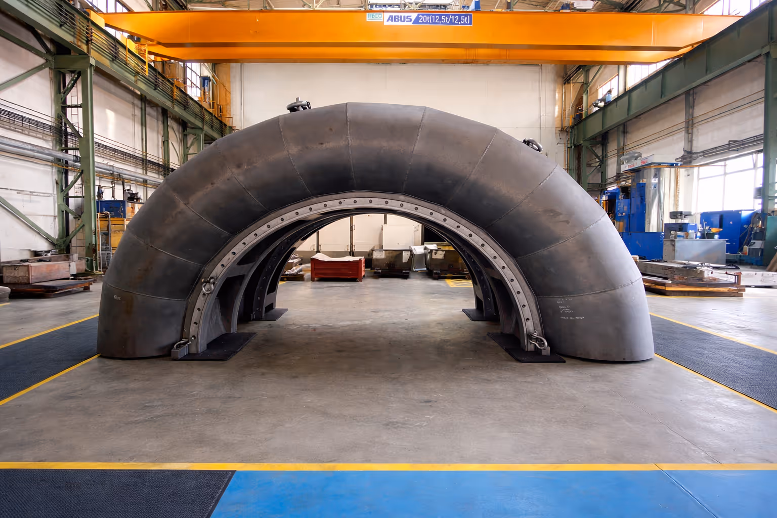 Workshop worker at a large metal industrial plant or machine on a concrete floor.
