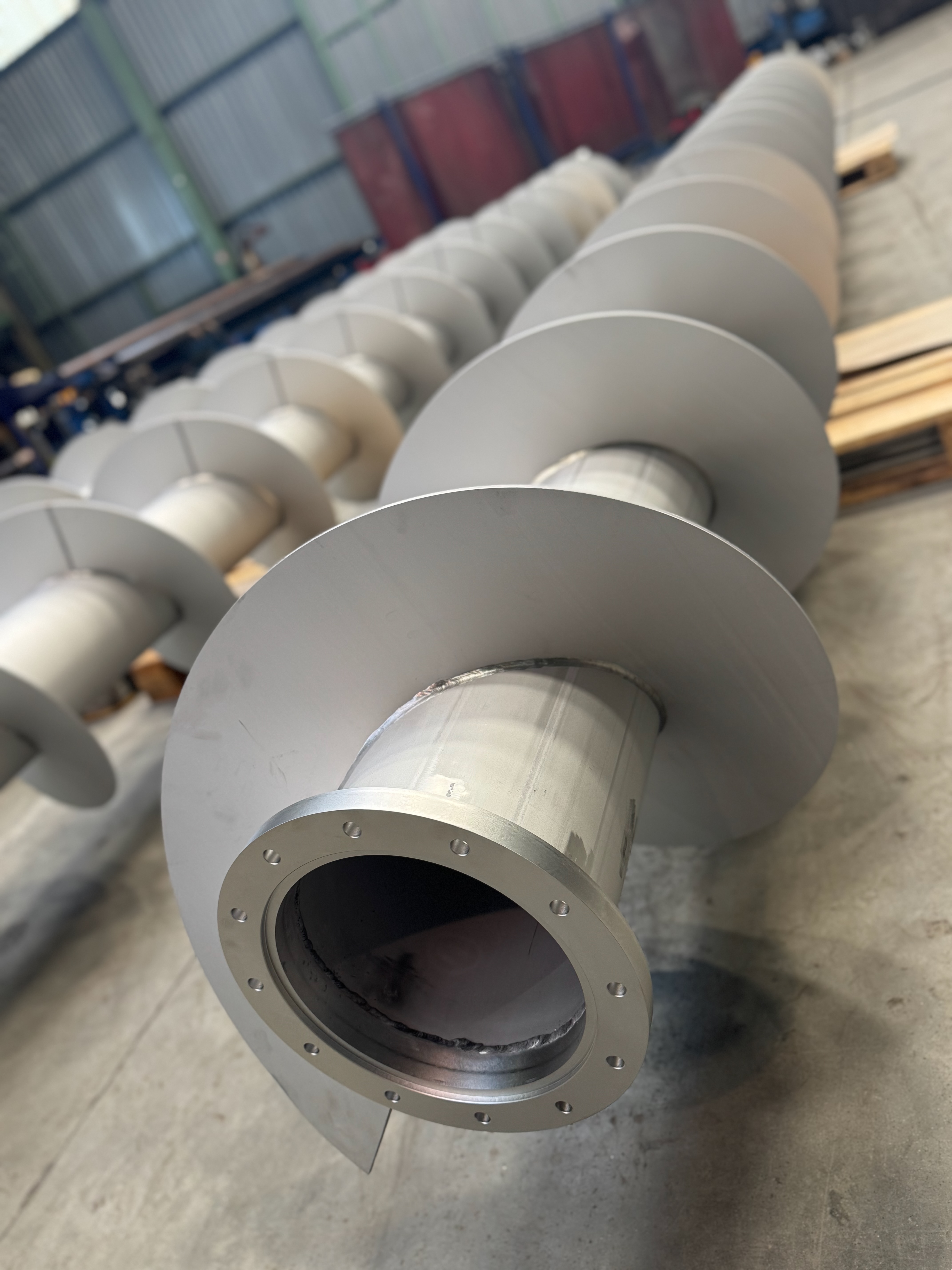 Dvě velké kovové průmyslové nádoby naložené na plošinovém návěsu na otevřeném prostranství.