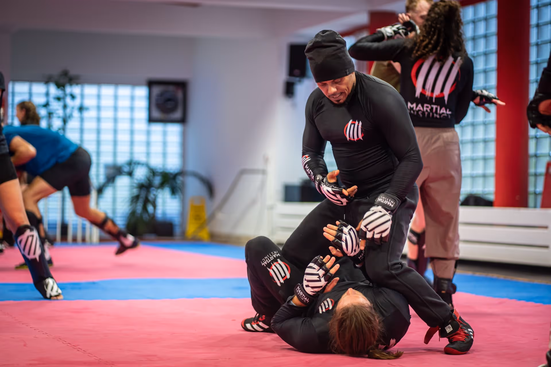 Junge Frau mit geflochtenem Haar und Boxbandagen lächelt beim Training in einem Fitnessstudio.