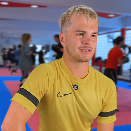Junger Mann mit kurzem blondem Haar trägt gelbes Nike-T-Shirt in einem Fitnessstudio.