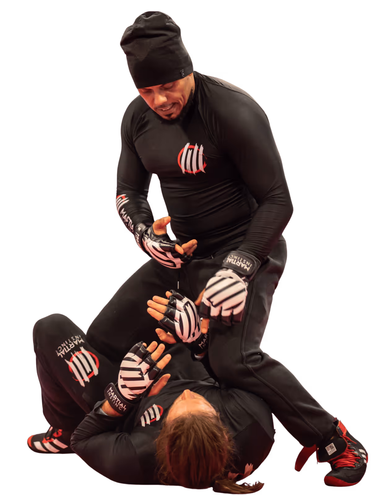 Zwei Personen in schwarzer Kampfsportkleidung und Handschuhen trainieren Bodenkampf in Nahaufnahme.