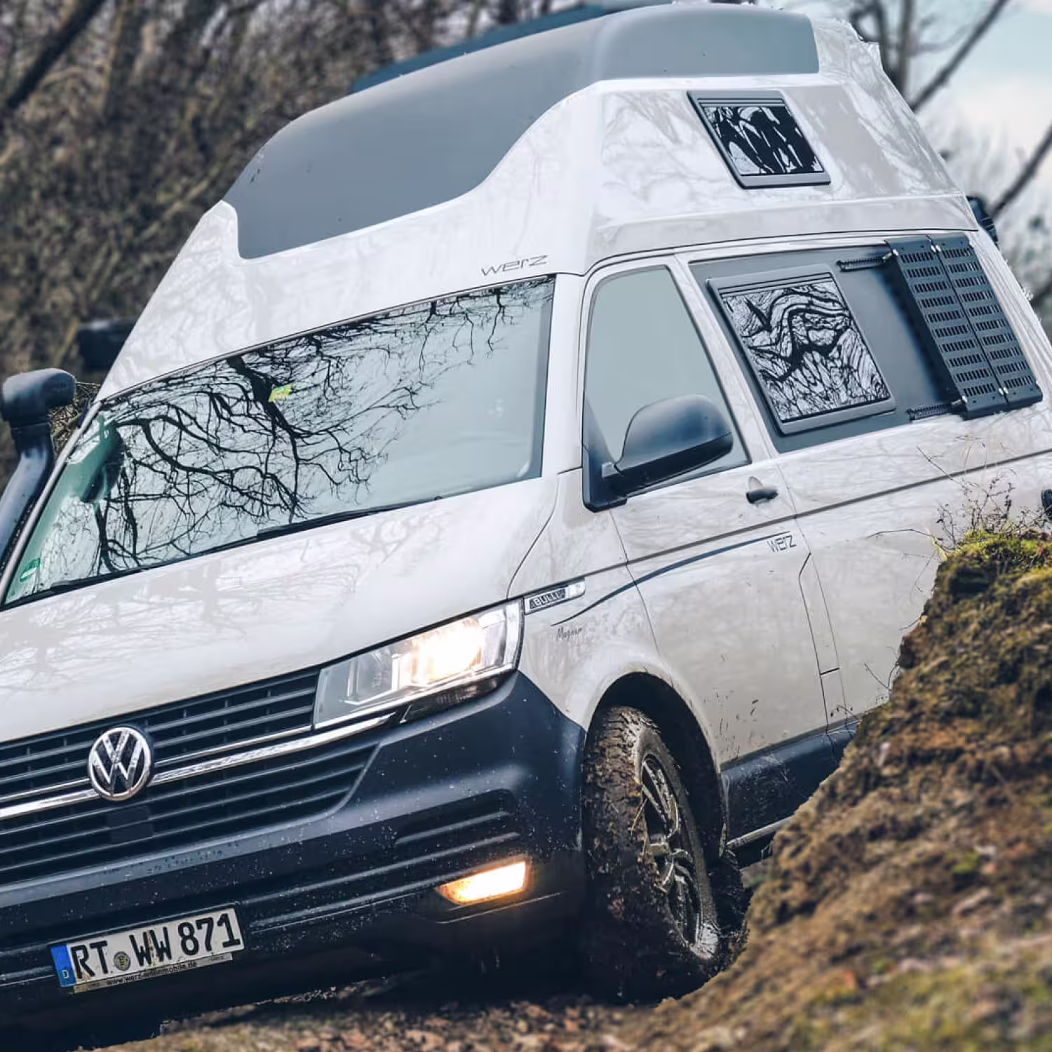 Volkswagen Camper Van Werz Magnum mit Hochdach fährt im schlammigen Waldgelände.