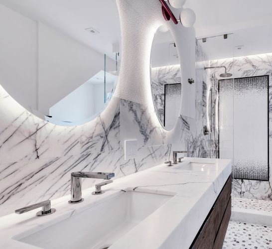 Modern bathroom with marble countertops and walls, two sinks with chrome faucets, round backlit mirrors, and a glass shower enclosure with a rainfall showerhead.
