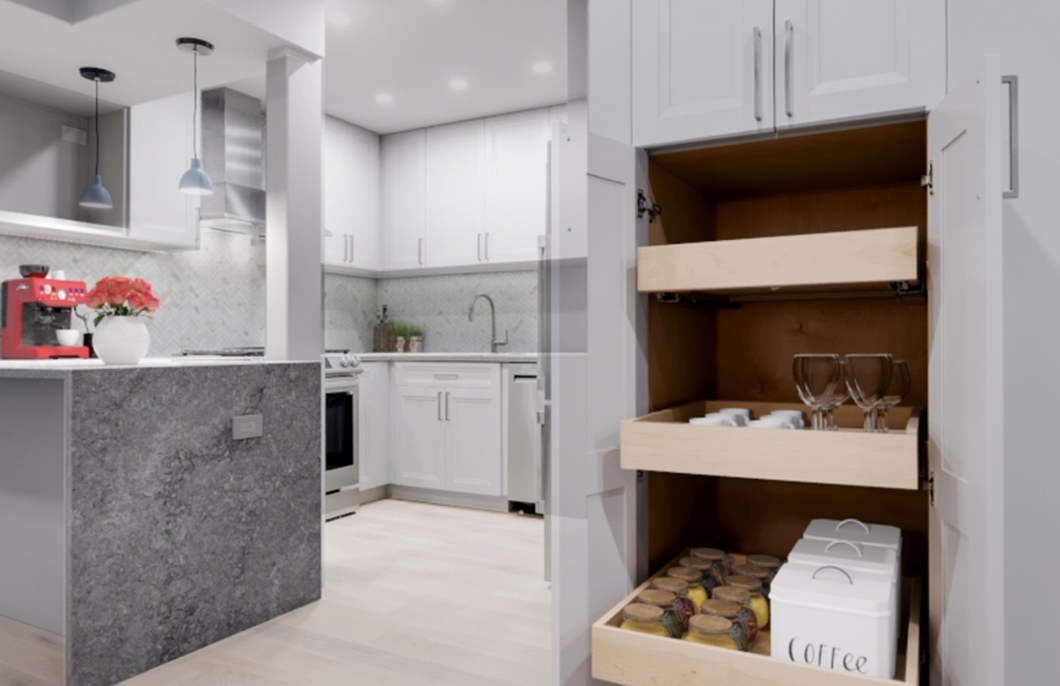 Modern white kitchen with marble island, open cabinet drawers containing glassware, coffee canisters, and jars.