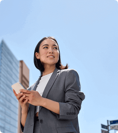 Woman with curly hair and gray coat opening the door of a yellow taxi in a city.