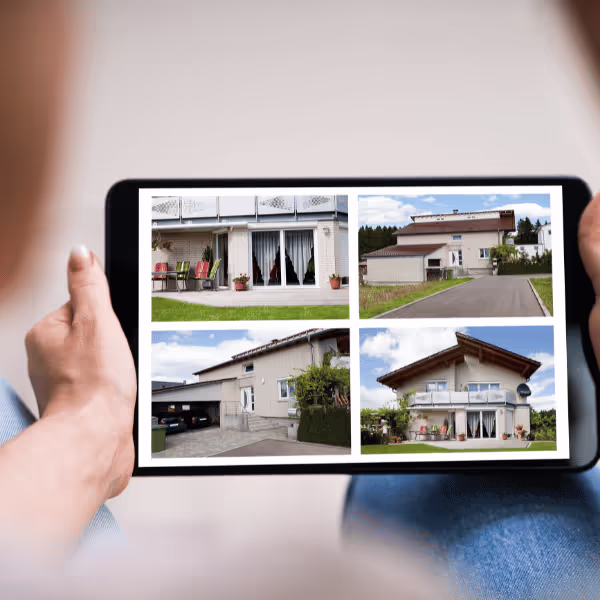 Osoba trzyma tablet z czterema zdjęciami różnych nowoczesnych domów jednorodzinnych.