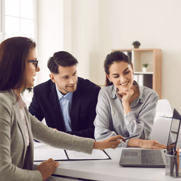 Troje młodych ludzi w biurze patrzy na ekran laptopa podczas spotkania.