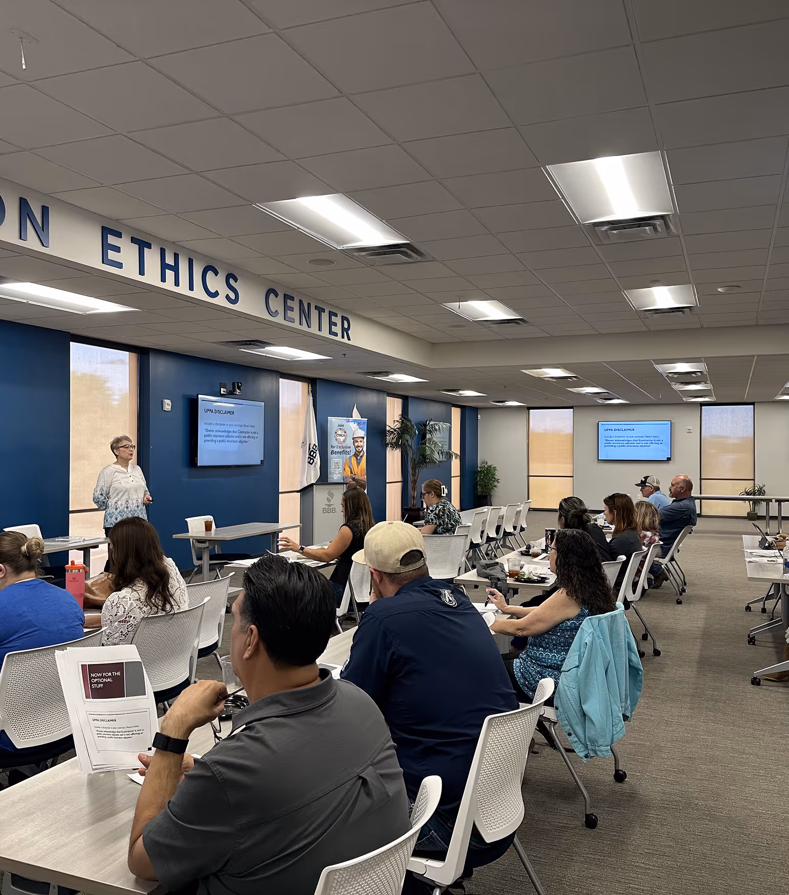 A presenter stands in front of a classroom with seated adults attending a presentation in the BBB Ethics Center.