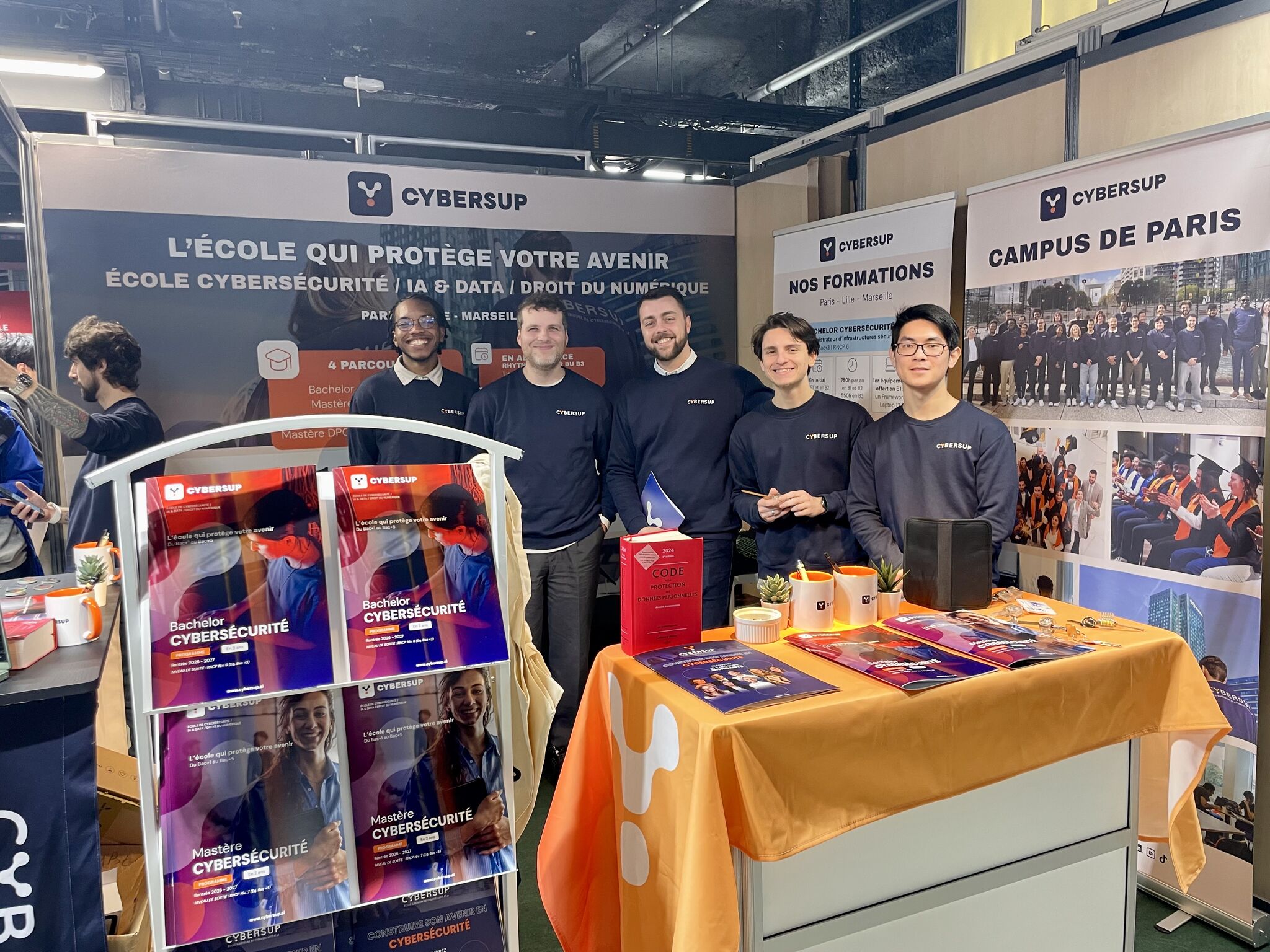 Jeunes adultes en discussion positive dans une pièce lumineuse, une femme pose la main sur l'épaule d'un homme souriant.