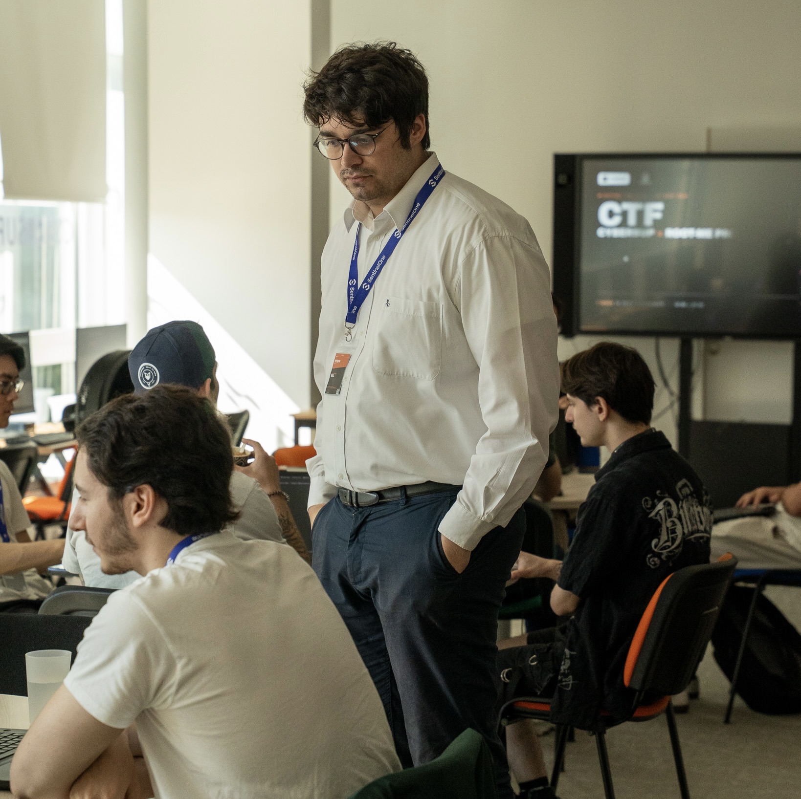 Une équipe diverse de professionnels vêtus de chemises orange et badges bleus collaborant autour d'appareils électroniques dans une salle de réunion.
