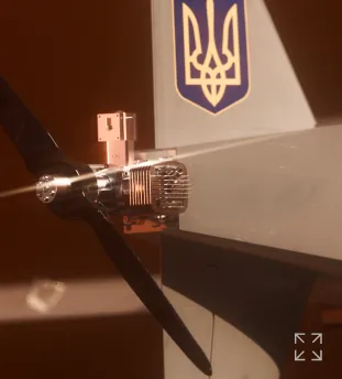 Close-up of a drone or small aircraft propeller and engine with a Ukrainian trident emblem on the aircraft body.