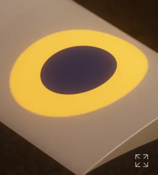 Close-up of a smooth gray surface with an oval dark blue center surrounded by a yellow ring.