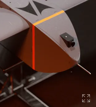 Close-up of a gray drone or aircraft nose with a black sensor and a red-orange light strip on the side.