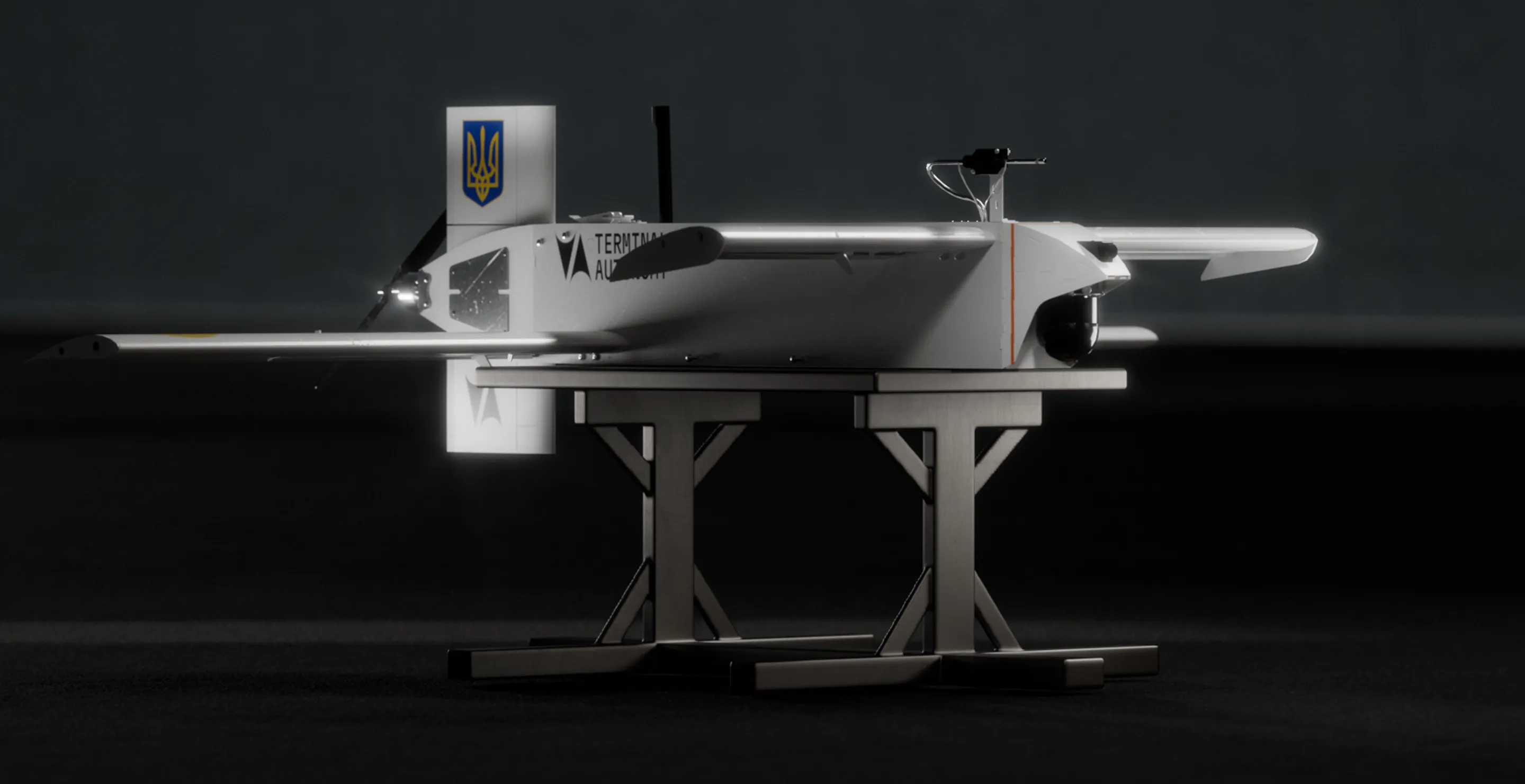 Side view of a white drone with wings and a camera mounted on the front, resting on a wooden stand against a dark background.