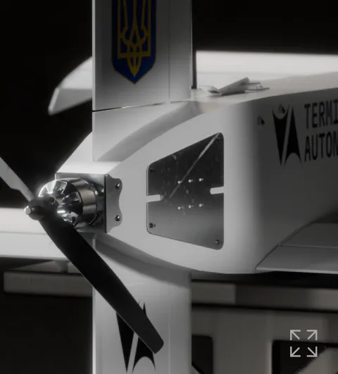 Close-up of a white drone with a propeller, featuring a metallic plate and partial text 'TERMI AUTON'.