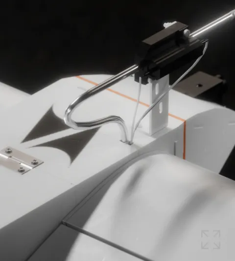 Close-up of a white mechanical or robotic device with metal rods, cables, and a hinge detail on a black background.